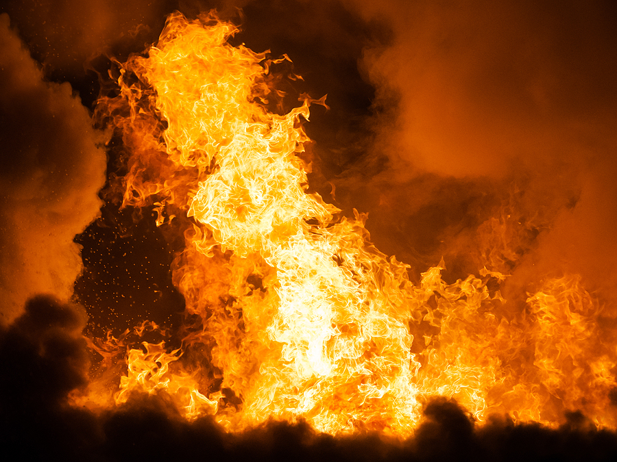 Large orange flames and thick black smoke engulfing a structure during a fire.