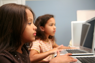 Two young children on computers at school
